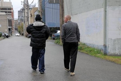 After picking up a patient from his home, Dr. Dixon walks with him to the Forbes Medical building in Oakland.